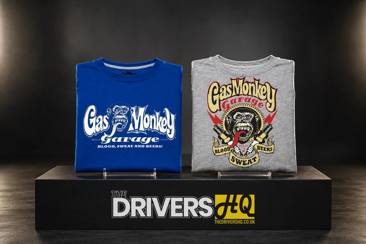 Folded Gas Monkey Garage OG Logo royal blue tee and Spark Plugs grey tee on a black display plinth