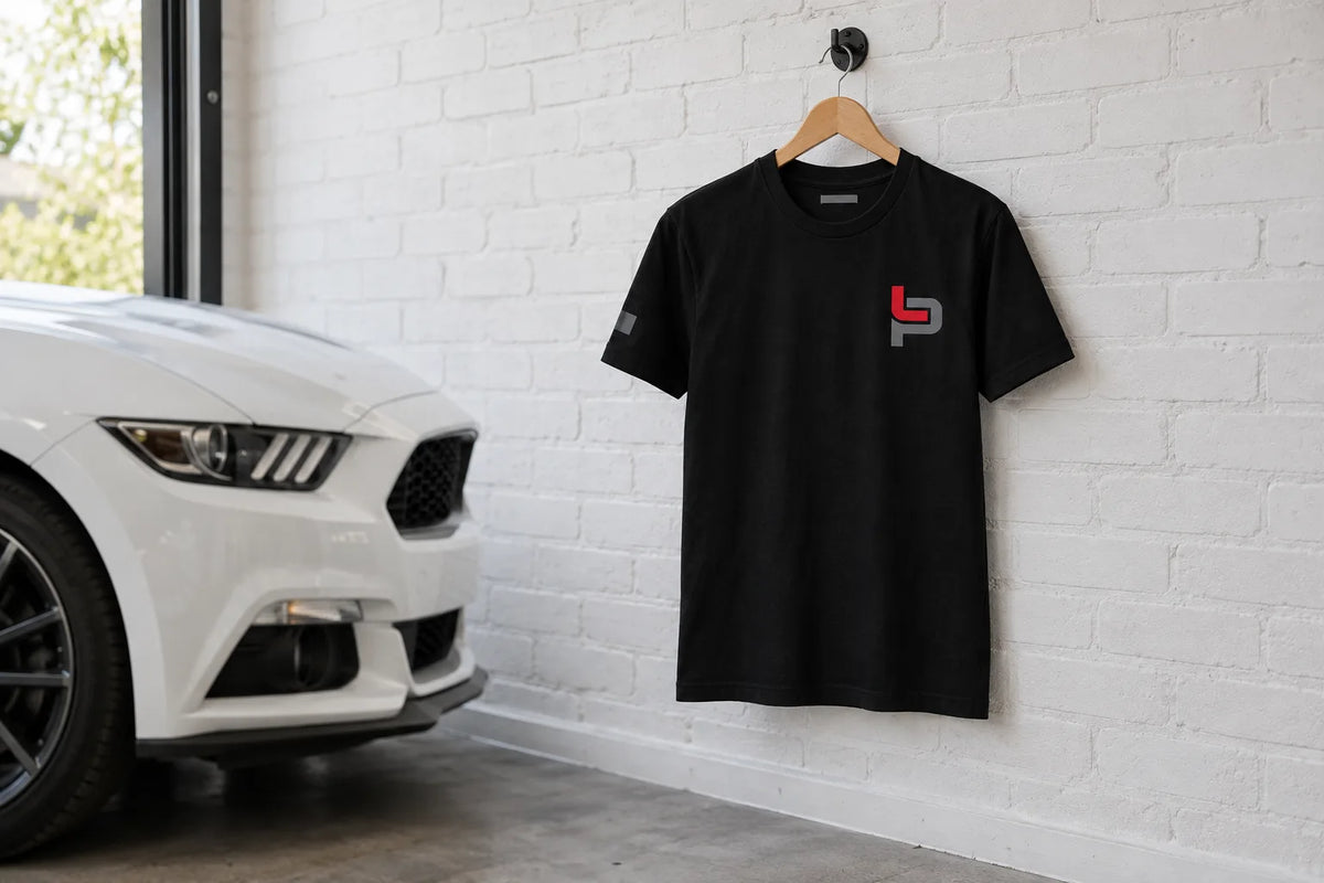 Black Hoonigan Leah Icon tee on a hanger in a garage beside a white sports car