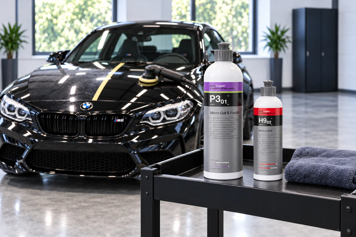 Koch-Chemie Micro Cut and Finish P3.01 and Heavy Cut H9.02 on a detailing trolley in front of a black BMW M2 Competition having its bonnet machine polished