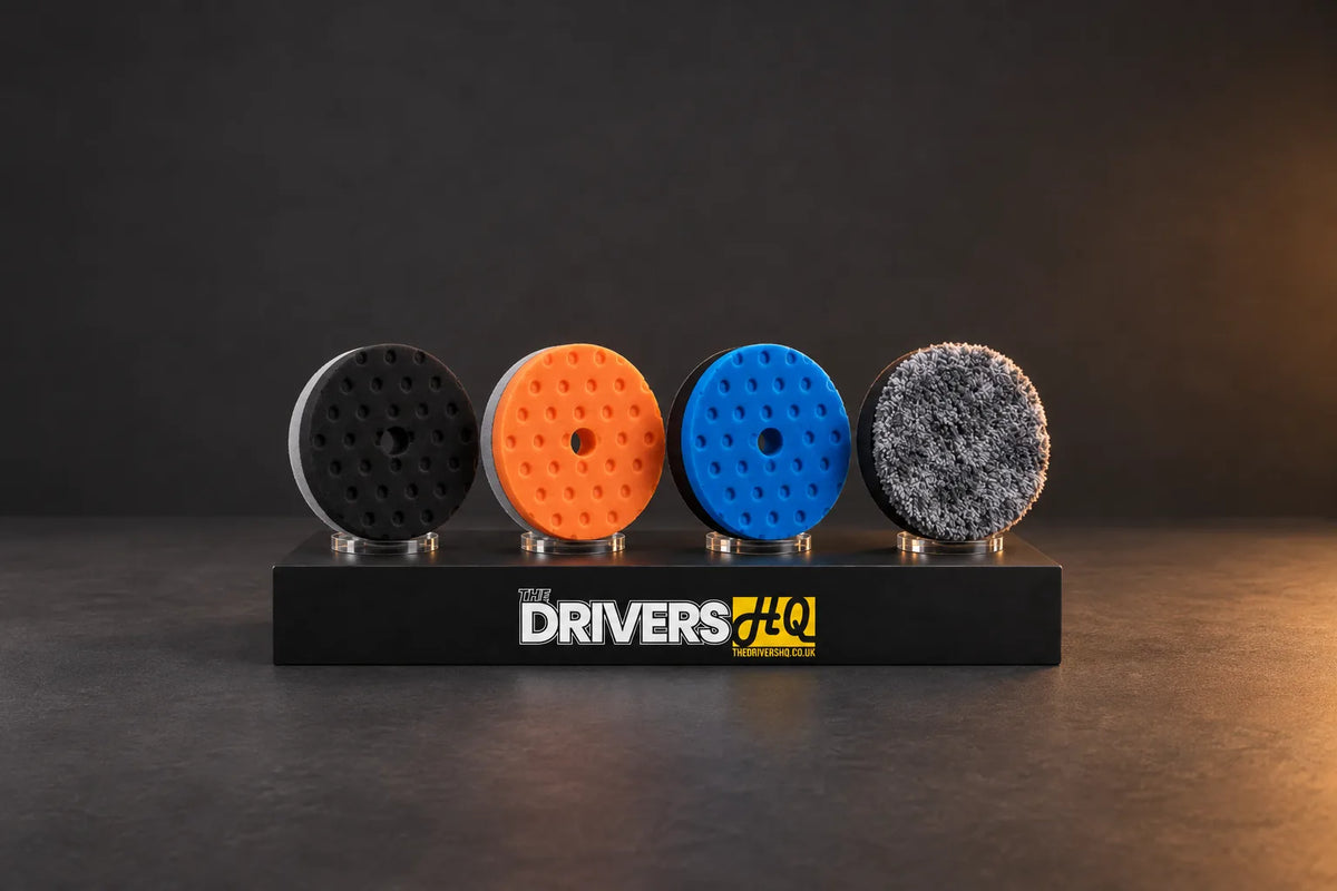 Lake Country HDO-CCS black and orange, SDO-CCS blue and microfibre 5.5 inch polishing pads on a black display plinth in a photo studio