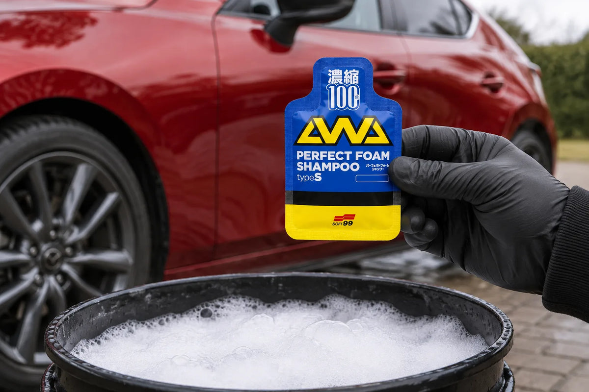 Soft99 Perfect Foam Shampoo type S sachet held over a bucket of foam beside a red car
