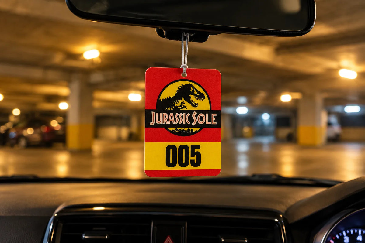 Sole Flavours Jurassic Sole 005 air freshener hanging from a rear-view mirror in a car park