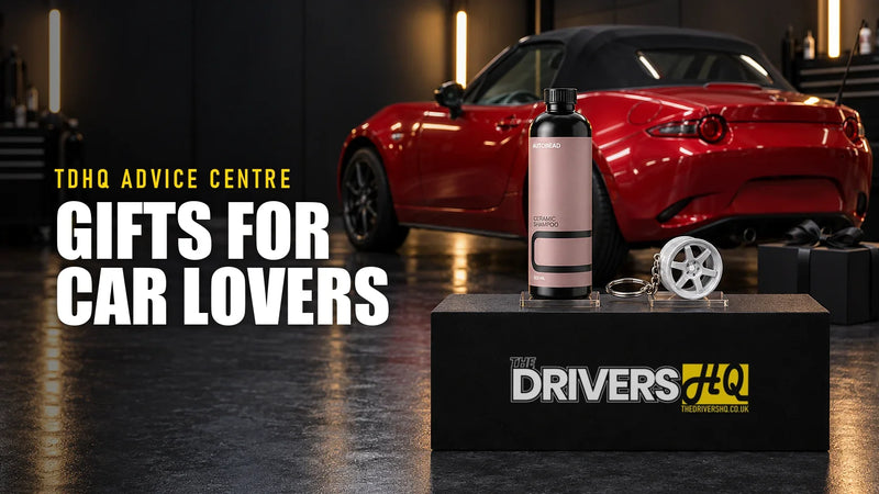 Gifts for car lovers UK: AutoBead Ceramic Shampoo and a wheel keyring on The Drivers HQ display plinth beside a gift box, in front of a red Mazda MX-5