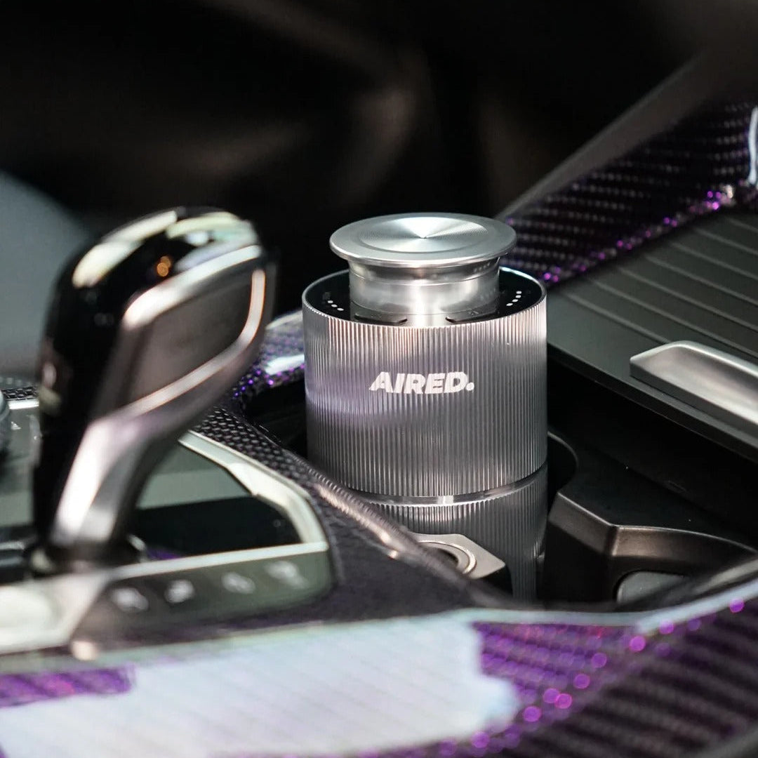 Car air freshener with 'AIRED' branding on a car dashboard.