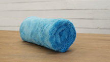 FibreKing Duplex edgeless cloth, a single light blue cloth rolled up on a wooden table