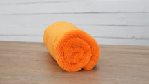 FibreKing Duplex edgeless cloth, a single orange cloth rolled up on a wooden table