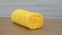 FibreKing Duplex edgeless cloth, a single yellow cloth rolled up on a wooden table