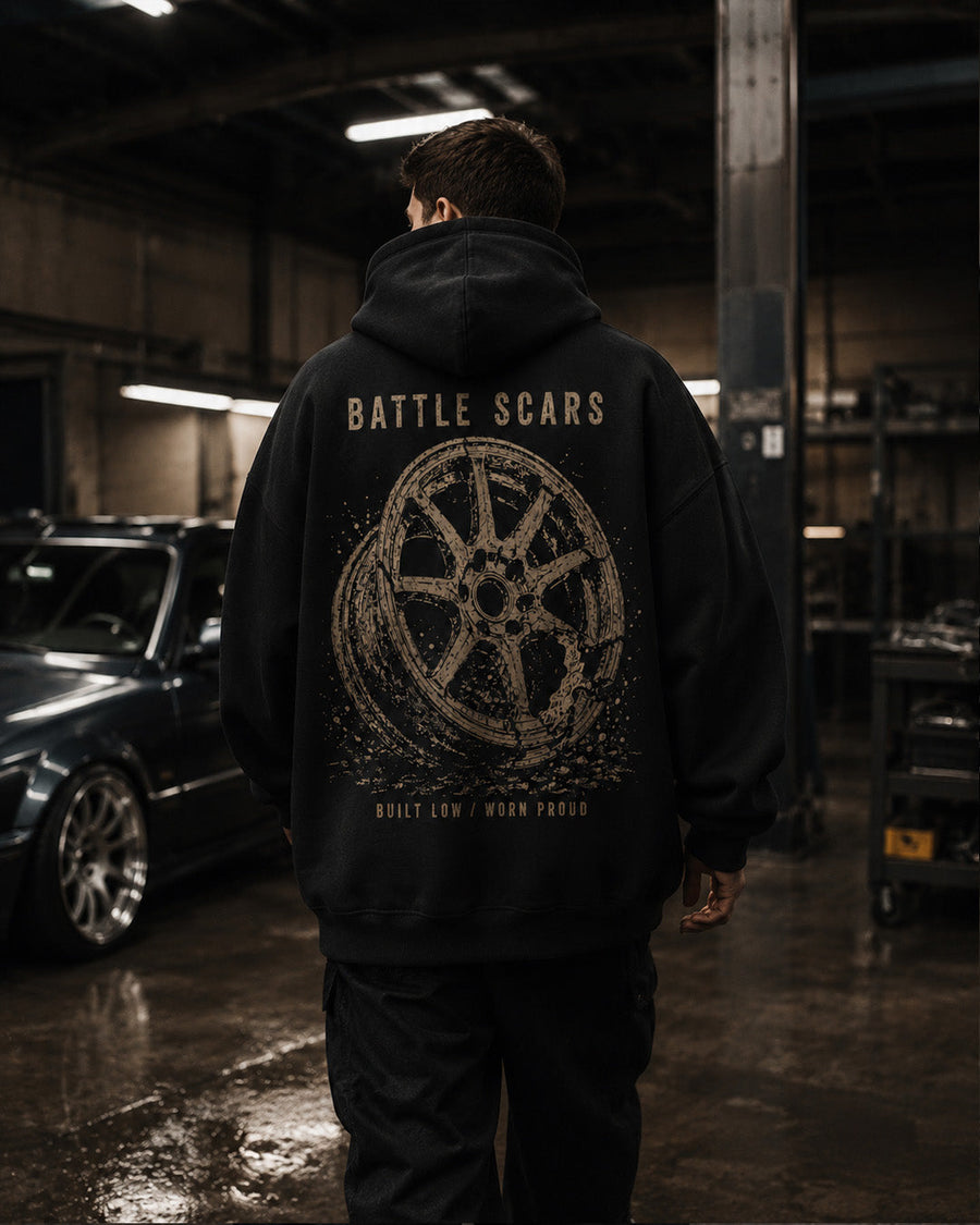 EuroStance Battle Scars Hoodie worn by a model in a garage, distressed wheel back print