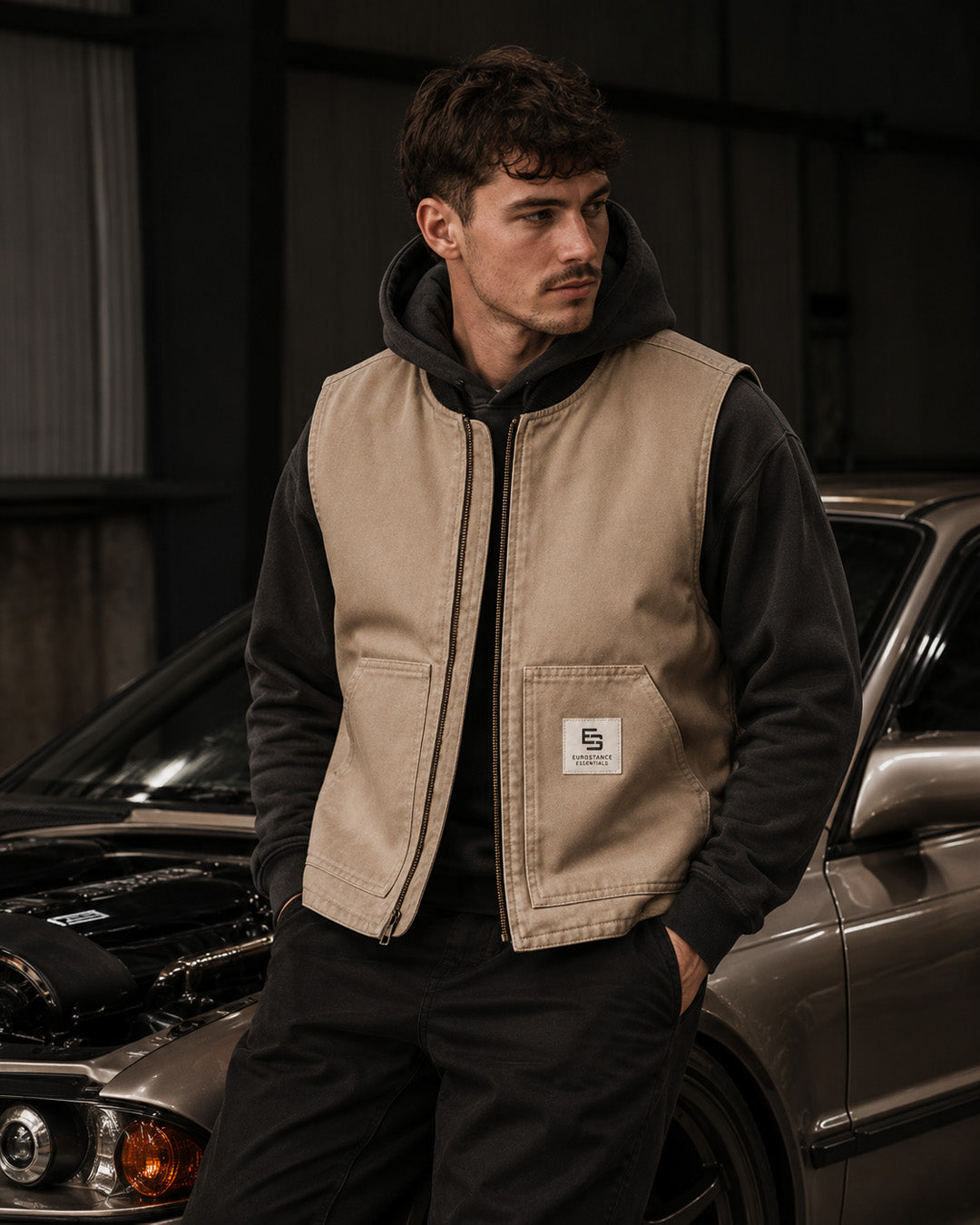 EuroStance Workwear Gilet in tan, worn zipped over a dark hoodie beside a car