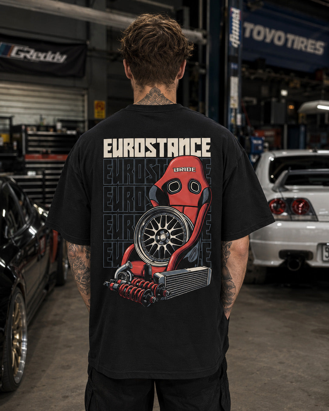 EuroStance Race Parts T-shirt worn in a garage, back print of red bucket seat and wheel