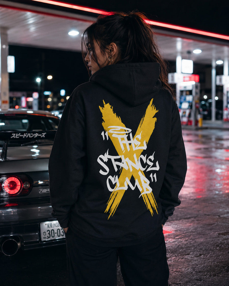 EuroStance Stance Club Hoodie, yellow cross back print worn at a petrol station at night