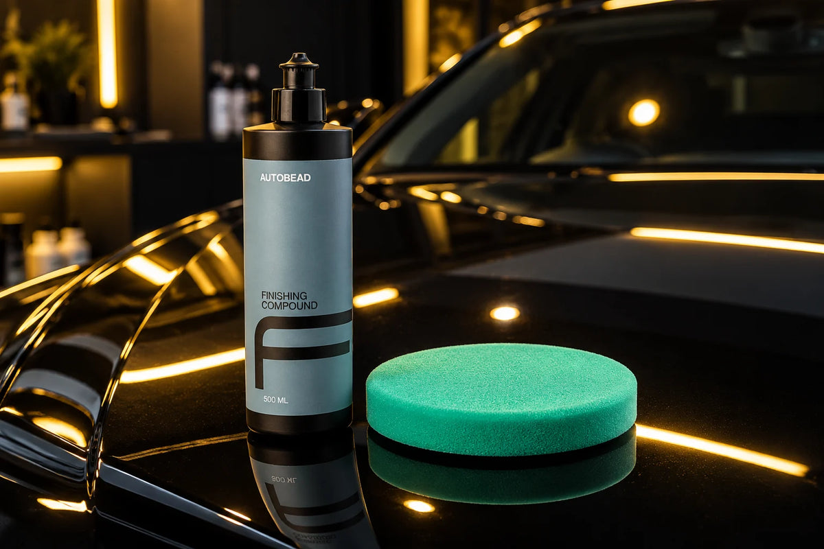 AutoBead Finishing Compound and a green Downforce Fine Cut foam pad on the glossy bonnet of a black car