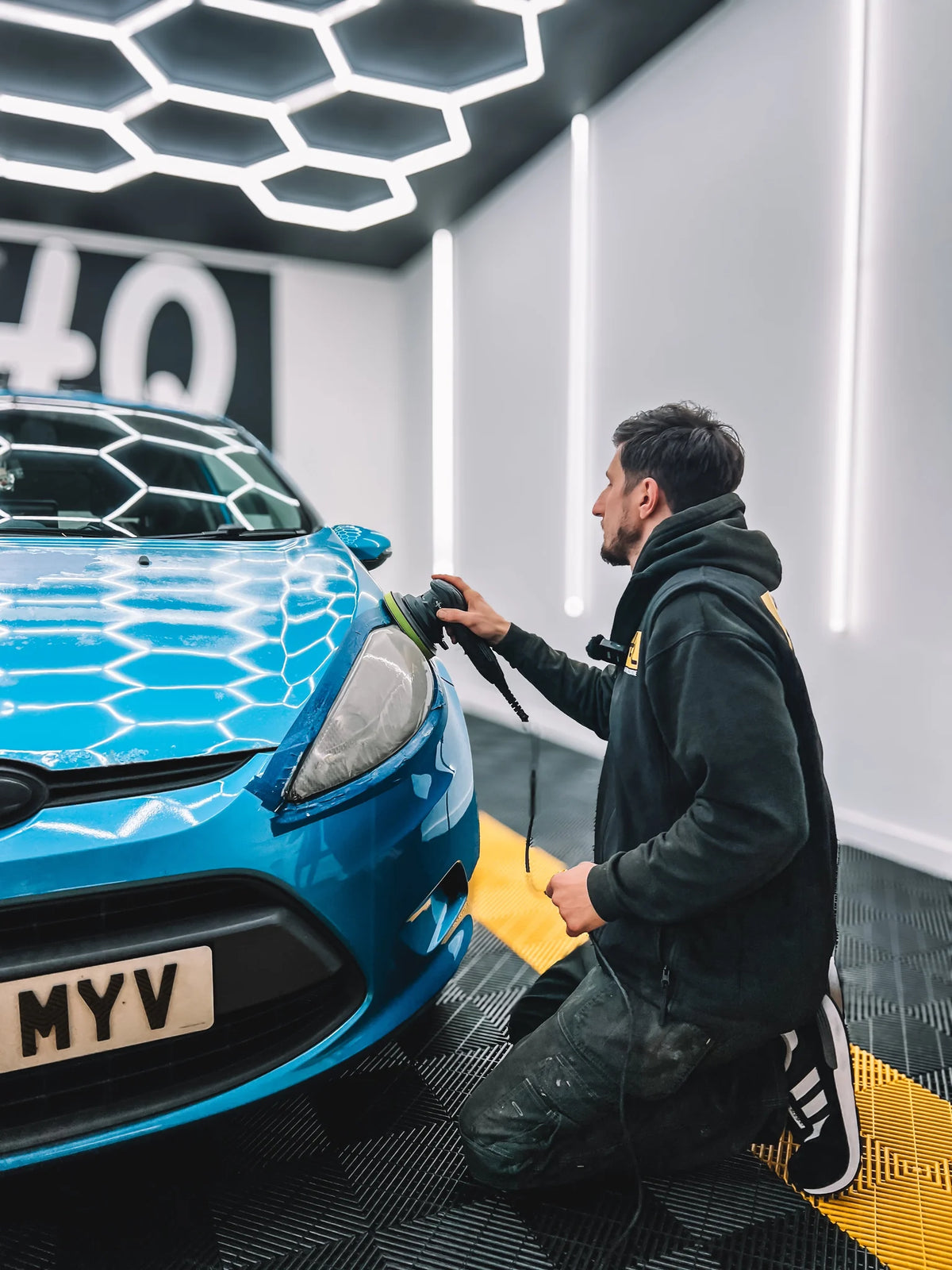 A Drivers HQ detailer machine polishing a blue car in the HQ detailing bay