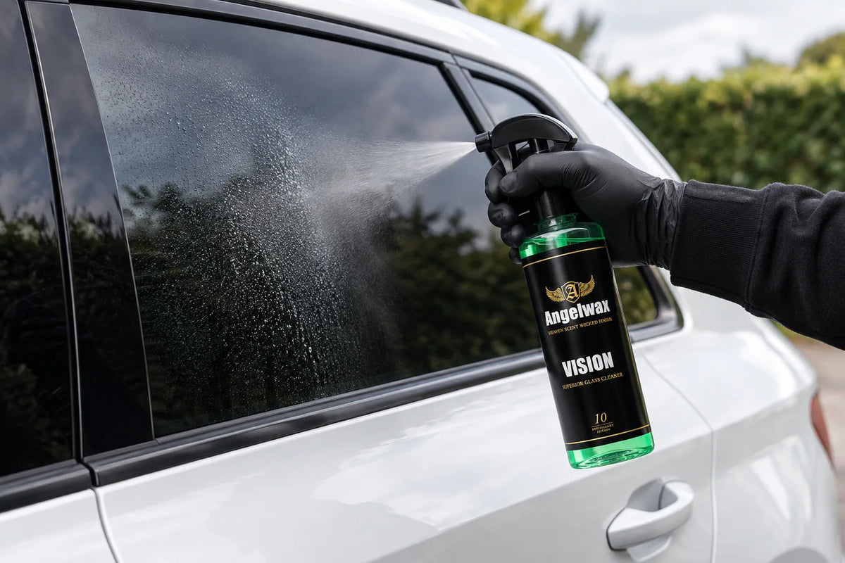 Angelwax Vision glass cleaner being sprayed onto the side window of a white car