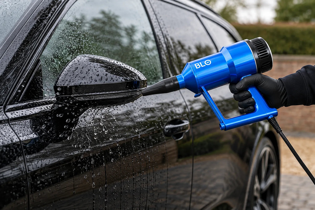 BLO Air-S hand held car dryer blowing water off the door mirror of a wet black car