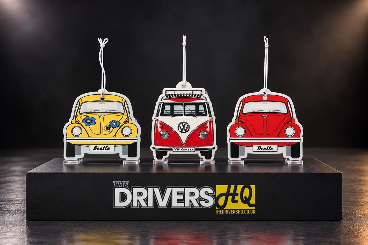 Yellow and red VW Beetle air fresheners and a red VW T1 camper van air freshener on a black display plinth
