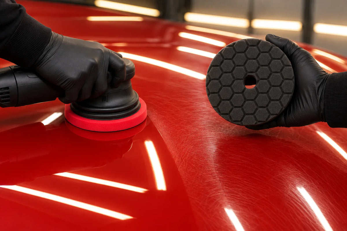 Chemical Guys red HEX-Logic Quantum pad on a dual action polisher on red paint, with the black Quantum pad held ready