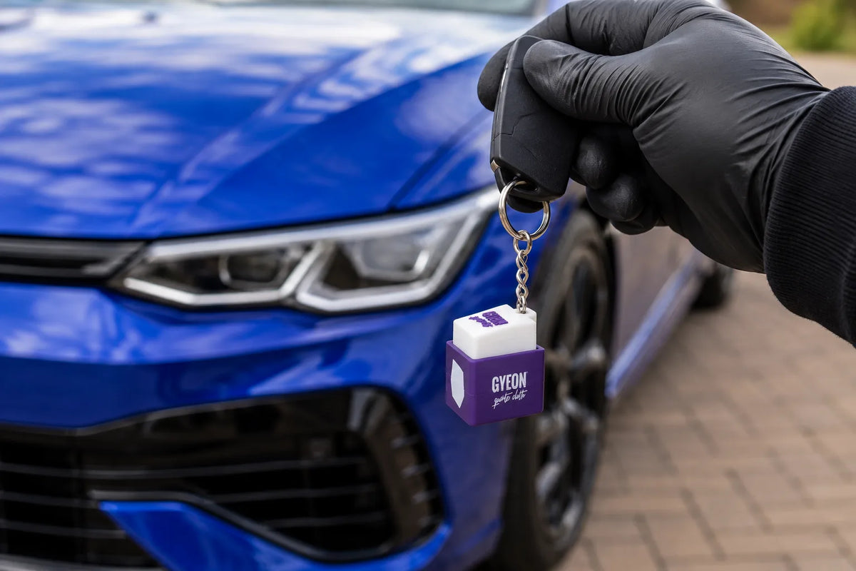 Gyeon Mohs+ key ring on a car key held in front of a blue hatchback