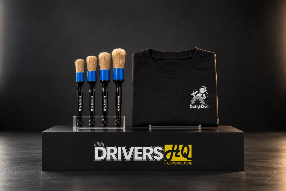 Four Poorboy's World boar's hair detailing brushes in a stand and a folded black Poorboy's World tee on a black display plinth