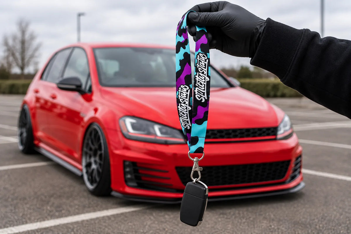 Strictly Static Blue Leopard lanyard with a car key held in front of a red hatchback