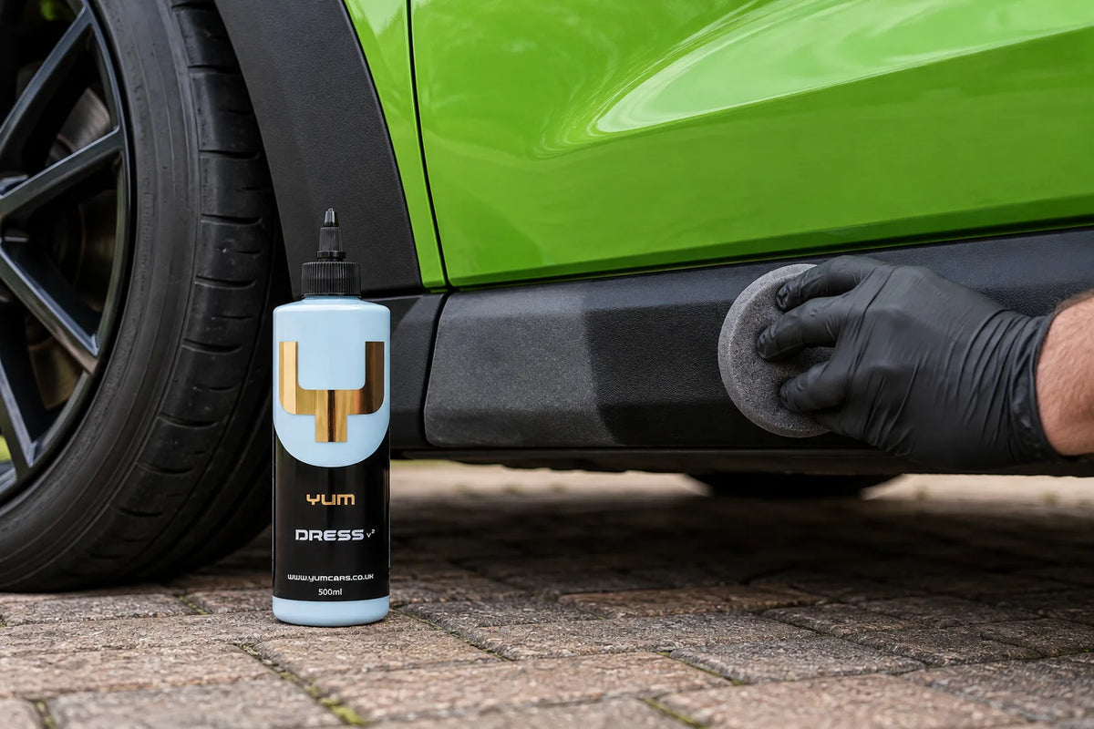 Yum Dress v2 bottle beside a car sill being dressed with a foam applicator