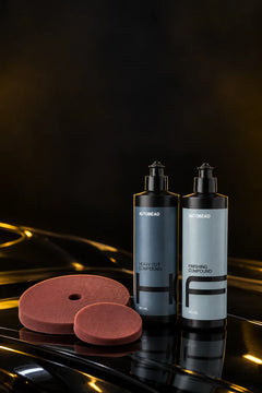 Correction kit: AutoBead Heavy Cut Compound and Finishing Compound with two Downforce Medium Cut foam pads on a glossy black bonnet