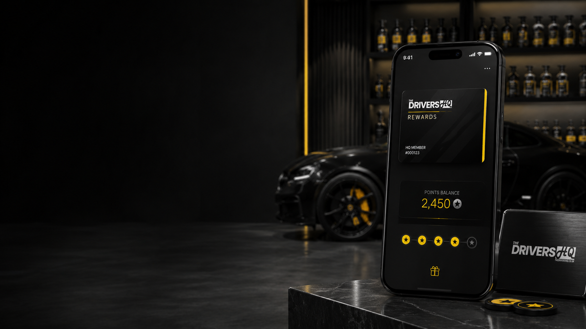 Phone showing a rewards card and points balance, with a black sports car behind it.