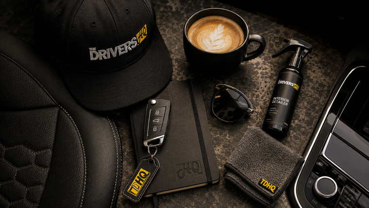 Cap, car key, notebook, sunglasses, coffee cup, spray bottle and microfibre cloth beside a car seat.