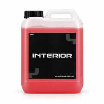 Yum Interior interior cleaner 5 litre jerrycan with coral red liquid and a black INTERIOR label, studio photo on white