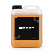 Yum Reset acidic shampoo 5 litre jerrycan with amber orange liquid and a black RESET label, studio photo on white